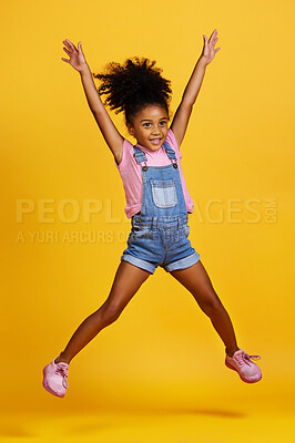 Studio portrait mixed race girl showing surprise with her hands raised isolated against a yellow background. Cute hispanic child posing inside. Happy and carefree kid lifting her hands upwards