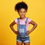 Studio portrait mixed race girl looking standing with her hands on her hips isolated against a yellow background. Cute hispanic child posing inside. Happy and cute kid smiling and looking confident