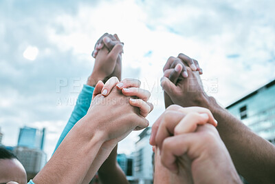 Diverse group of people holding hands with arms raised to express unity, support and trust. Multiracial people cheering while huddled to celebrate winning achievement. Joining together for collaboration and solidarity