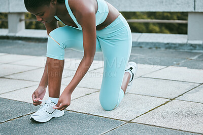 Buy stock photo One fit young african american woman tying her shoelaces while exercising outside. Black athlete fastening sneaker footwear for a comfortable fit and to prevent tripping during a training workout in the city