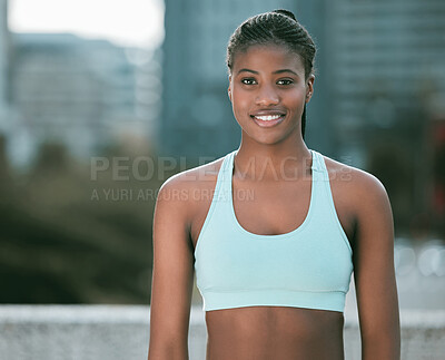 Portrait of one confident young african american woman exercising outdoors. Determined female athlete looking happy and motivated for training workout in the city