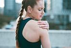 One young caucasian woman holding her sore shoulder while exercising outdoors. Female athlete suffering with painful arm injury from fractured joint and inflamed muscles during workout. Struggling with stiff body cramps causing discomfort and strain