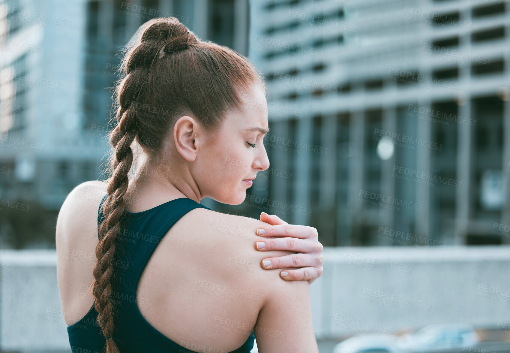 Buy stock photo One young caucasian woman holding her sore shoulder while exercising outdoors. Female athlete suffering with painful arm injury from fractured joint and inflamed muscles during workout. Struggling with stiff body cramps causing discomfort and strain