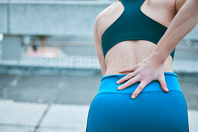 Buy stock photo Closeup of one caucasian woman holding her sore lower back while exercising outdoors. Female athlete suffering with painful spine injury from fractured joint and inflamed muscles during workout. Struggling with stiff body cramps causing discomfort