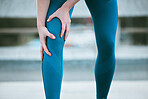 Closeup of one caucasian woman holding her sore knee while exercising outdoors. Female athlete suffering with painful leg injury from fractured joint and inflamed muscles during workout. Struggling with stiff body cramps causing discomfort and strain