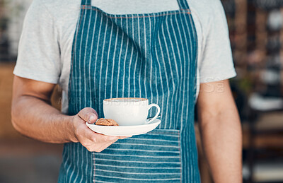 Buy stock photo Closeup of one hispanic waiter serving a cup of coffee with a cookie while working in a cafe. Hands of barista holding teacup on saucer filled with warm latte or cappuccino for customer