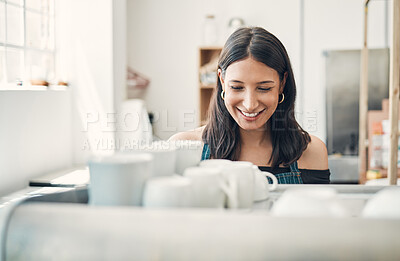 Buy stock photo One happy hispanic waitress using a coffee machine to prepare a hot beverage in a cafe. Happy barista making a warm drink to serve customers in a coffeeshop