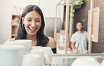 One happy hispanic waitress using a coffee machine to prepare a hot beverage in a cafe. Happy barista making a warm drink to serve customers in a coffeeshop