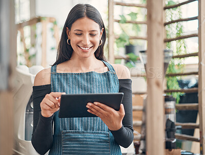 Buy stock photo Shot of one young hispanic waitress using a digital tablet device while working in a store or cafe. Happy woman planning and browsing online while managing a successful restaurant startup