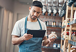 Shot of one young hispanic waiter using a digital tablet device while working in a store or cafe. Mixed race man checking inventory and stock of products while planning and browsing online