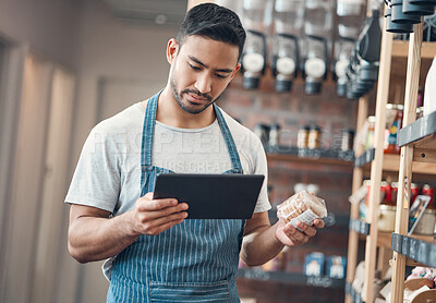 Buy stock photo Shot of one young hispanic waiter using a digital tablet device while working in a store or cafe. Mixed race man checking inventory and stock of products while planning and browsing online