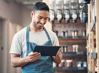 Shot of one young hispanic waiter using a digital tablet device while working in a store or cafe. Happy man checking inventory and stock of products while planning and browsing online