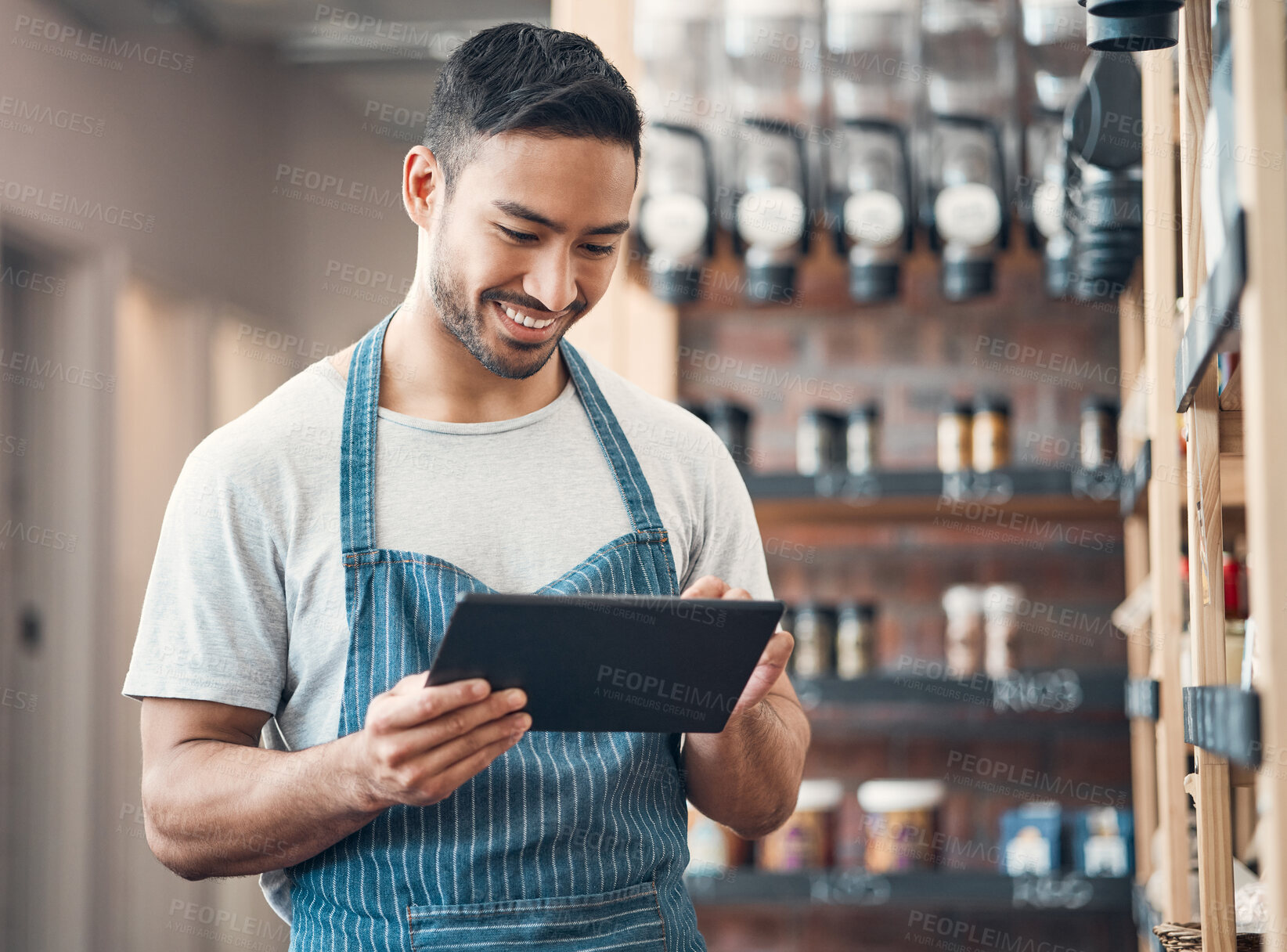 Buy stock photo Shot of one young hispanic waiter using a digital tablet device while working in a store or cafe. Happy man checking inventory and stock of products while planning and browsing online