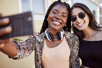 Buy stock photo Best friends having fun and taking a selfie outdoors. Two multiethnic female friends spending time together and taking photos for social media on smartphone