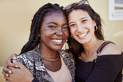 Buy stock photo Portrait of two girls hugging and smiling while standing on sidewalk, feeling joyful and happy together. Multiethnic female friends in city