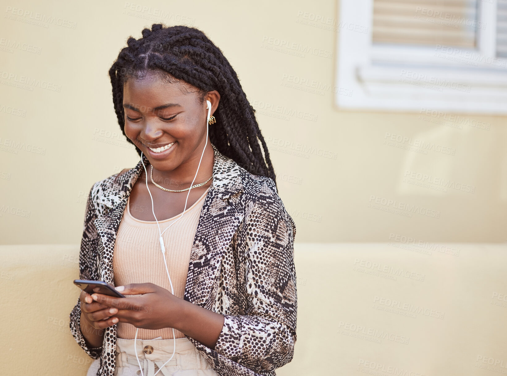 Buy stock photo Stylish african american woman with using earphones to listen to music on smartphone or watch funny video online. Smiling young woman using mobile app while walking on city street