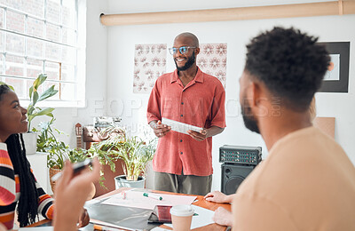 Group of diverse businesspeople having a meeting in a modern office at work. Young happy african american businessman wearing glasses doing a presentation of an idea using a digital tablet in a boardroom with colleagues. Businesspeople planning together
