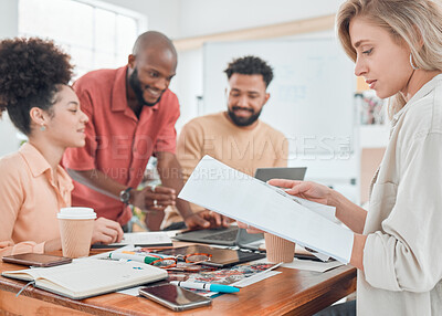 Buy stock photo Group of happy diverse businesspeople having a meeting in a modern office at work. Young caucasian businesswoman reading a report while sitting at a table with colleagues. Creative businesspeople planning together