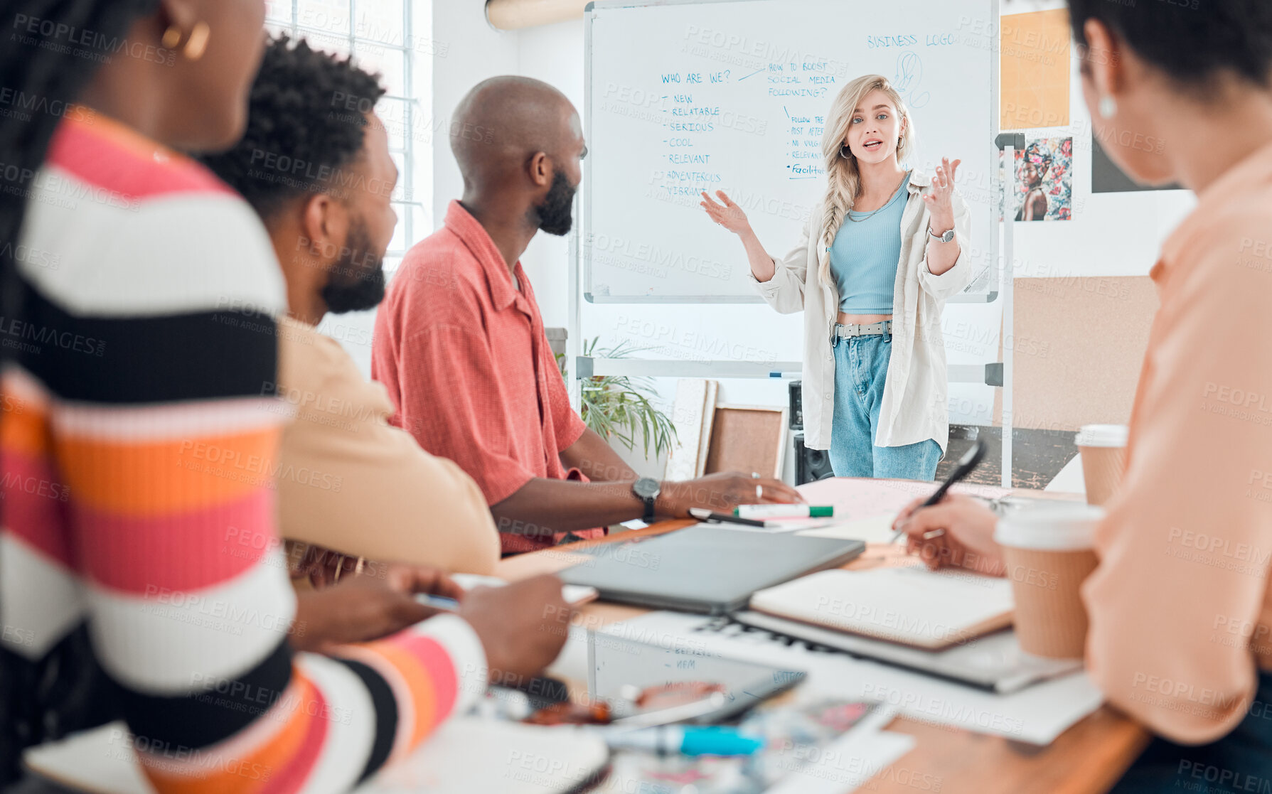 Buy stock photo Group of diverse businesspeople having a meeting in a modern office at work. Young serious caucasian businesswoman talking while doing a presentation of an idea on a whiteboard in a boardroom with colleagues. Businesspeople planning together
