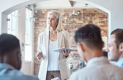 Buy stock photo Beautiful mature architect woman using a digital tablet while addressing her colleagues and coworkers while meeting in the boardroom. Discussing and brainstorming plans for their development project