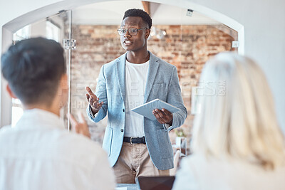 Buy stock photo Young african american architect man using a digital tablet and addressing his colleagues and coworkers while meeting in the boardroom. Discussing and brainstorming plans for their development project