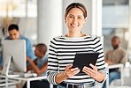 Portrait of a cheerful mixed race businesswoman working on a digital tablet at work. Happy hispanic female smiling while using social media on a digital tablet. Businessperson checking an email on a digital tablet