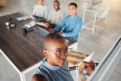 Group of diverse businesspeople having a meeting in an office at work. Young african american businesswoman writing an idea on a whiteboard in a boardroom with colleagues. Businesspeople planning together