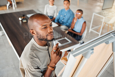 Group of diverse businesspeople having a meeting in an office at work. Young focused african american businessman thinking of an idea on a whiteboard in a boardroom with colleagues. Businesspeople planning together