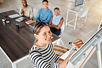 Group of diverse businesspeople having a meeting in an office at work. Young happy mixed race businesswoman smiling while writing an idea on a whiteboard in a boardroom with colleagues. Businesspeople planning together
