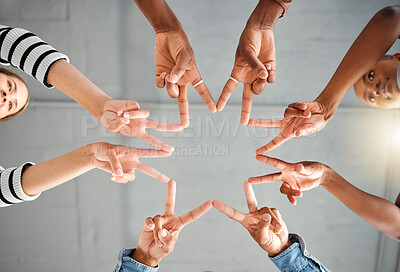 Group of businesspeople making a star shape with their hands together in an office at work. Business professionals having fun making a hand gesture. Colleagues showing a peace sign from below