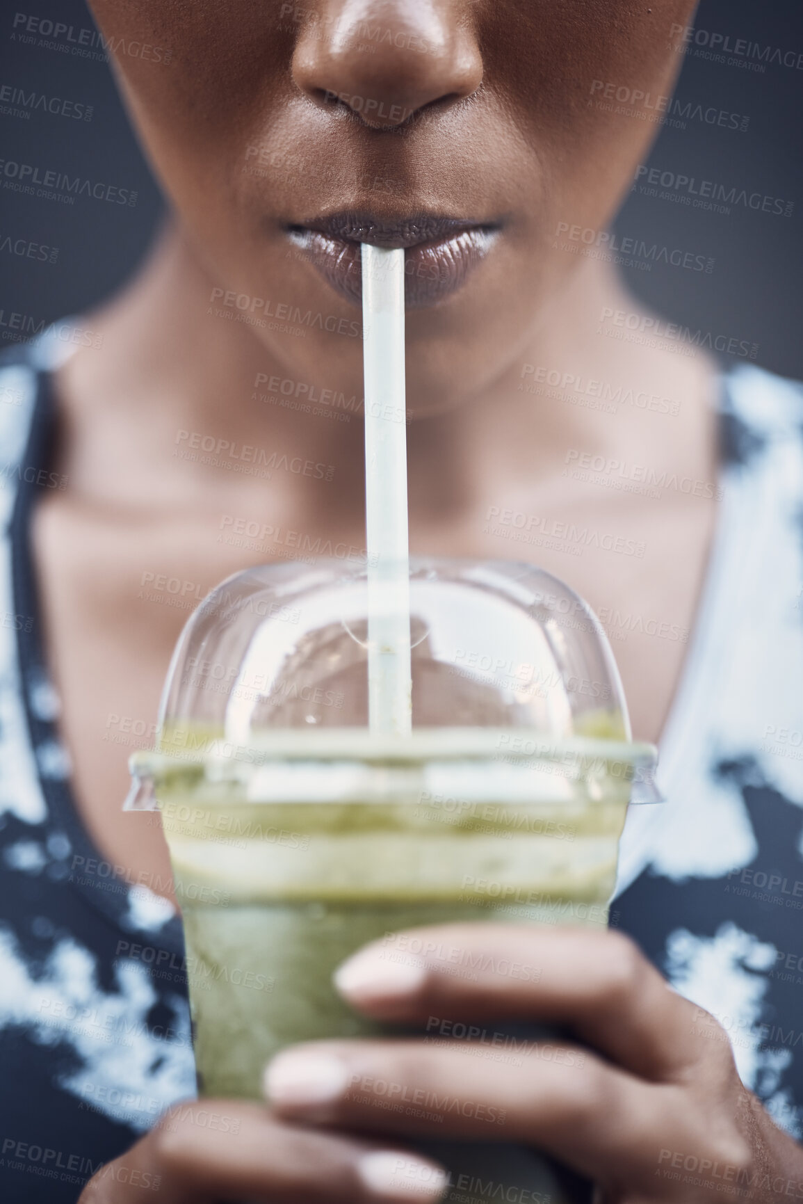 Buy stock photo Closeup of one active woman drinking a healthy green detox smoothie while exercising outdoors. Female athlete sipping on fresh fruit juice with straw in plastic cup to cleanse and provide energy for training. Wholesome drink with vitamins and nutrients