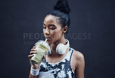 Buy stock photo One active young mixed race woman drinking a healthy green detox smoothie while exercising outdoors. Female athlete sipping on fresh nutritious fruit juice with straw in plastic cup to cleanse, provide energy and vitamins for training