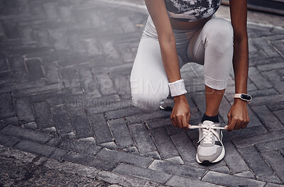 Buy stock photo Closeup of one mixed race woman tying her shoelaces while exercising outdoors. Athlete fastening sneaker footwear for a comfortable fit and to prevent tripping while getting ready for cardio training workout or run in the city