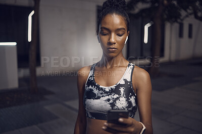 Buy stock photo One fit young mixed race woman listening to music with wireless earphones from a cellphone while taking a break from exercise outdoors. Focused female athlete texting and using fitness apps online while browsing social media and watching workout tutorials
