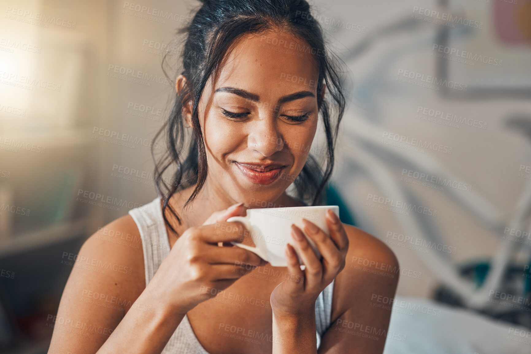 Buy stock photo A beautiful young Hispanic woman enjoying a warm cup of coffee for breakfast. One mixed race female drinking tea while sitting in bed and daydreaming