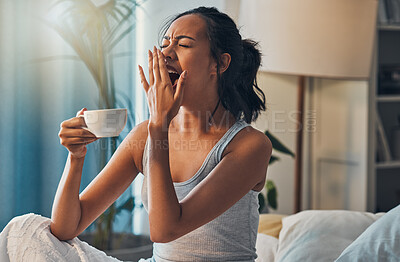 Buy stock photo A young mixed race woman yawning while lying in bed and drinking coffee. An attractive Hispanic female waking up from a her sleep and getting ready to begin her day