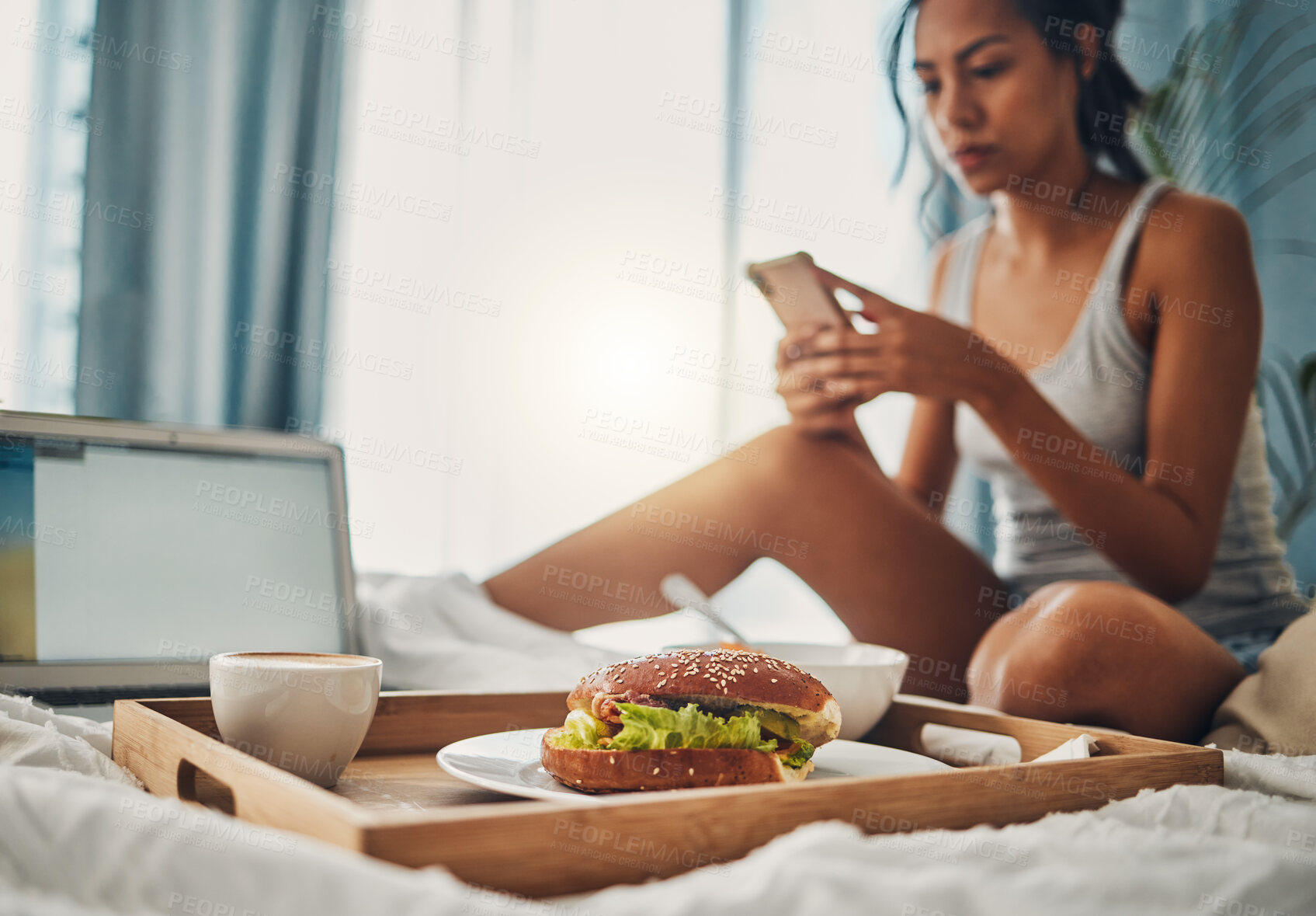 Buy stock photo A beautiful young Hispanic woman checking social media on her cellphone while enjoying bed in breakfast at a hotel