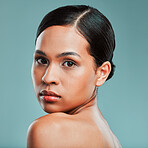 Portrait of a young beautiful mixed race woman with smooth soft skin posing against a green studio background. Attractive Hispanic female with stylish makeup posing in studio