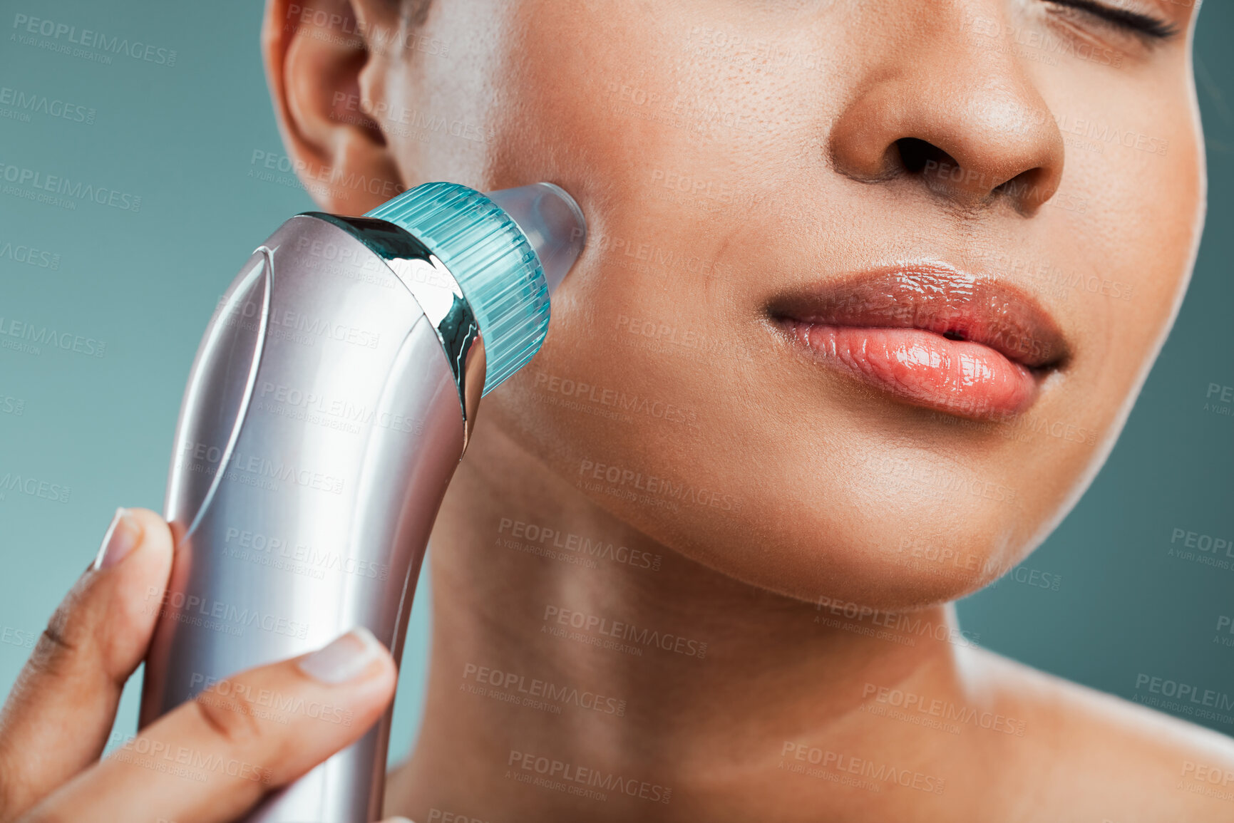 Buy stock photo Young mixed race woman using a pore and blackhead vacuum suction machine against.a green studio background. Young latina female grooming her smooth soft skin