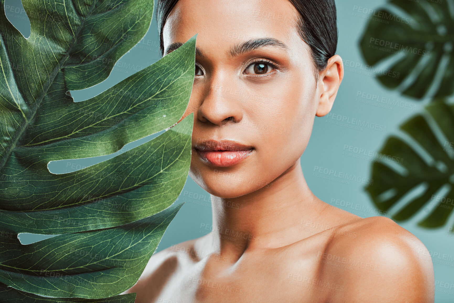 Buy stock photo Studio portrait of an attractive young mixed race woman posing with a leaf against a green background. Latin female posing with a plant with her smooth soft skin