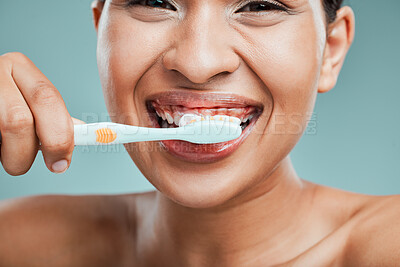 Buy stock photo Studio portrait of an attractive young woman brushing her teeth against a green background.Latin female taking care of her dental hygiene and oral health