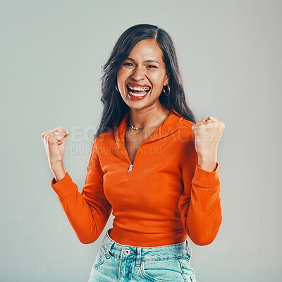 Buy stock photo Portrait of mixed race woman isolated against grey studio background with copyspace. Young hispanic standing alone and celebrating success. Excited model making fists with hand gesture while cheering