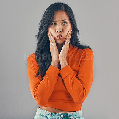 Buy stock photo Mixed race woman isolated on grey studio background with copyspace and feeling silly. Beautiful young hispanic standing alone and making goofy facial expression. One pouting model feeling forgetful