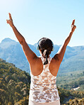 Rear view of a mature woman standing with her hands raised to the sky feeling free and overlooking a beautiful mountain view