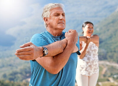 Buy stock photo Senior man stretching and taking a deep breath while exercising outdoors. Mature people practicing yoga during class in nature