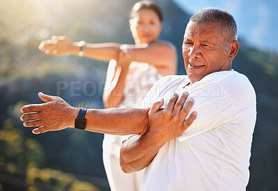 Buy stock photo Senior man stretching his arms while exercising outdoors on a sunny day. Mature people practicing yoga together in nature staying healthy and active during retirement. Wearing smart watch