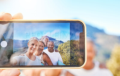 Buy stock photo Close up of device screen while active senior people pose together for a selfie outdoors. Group of mature people exercising in nature