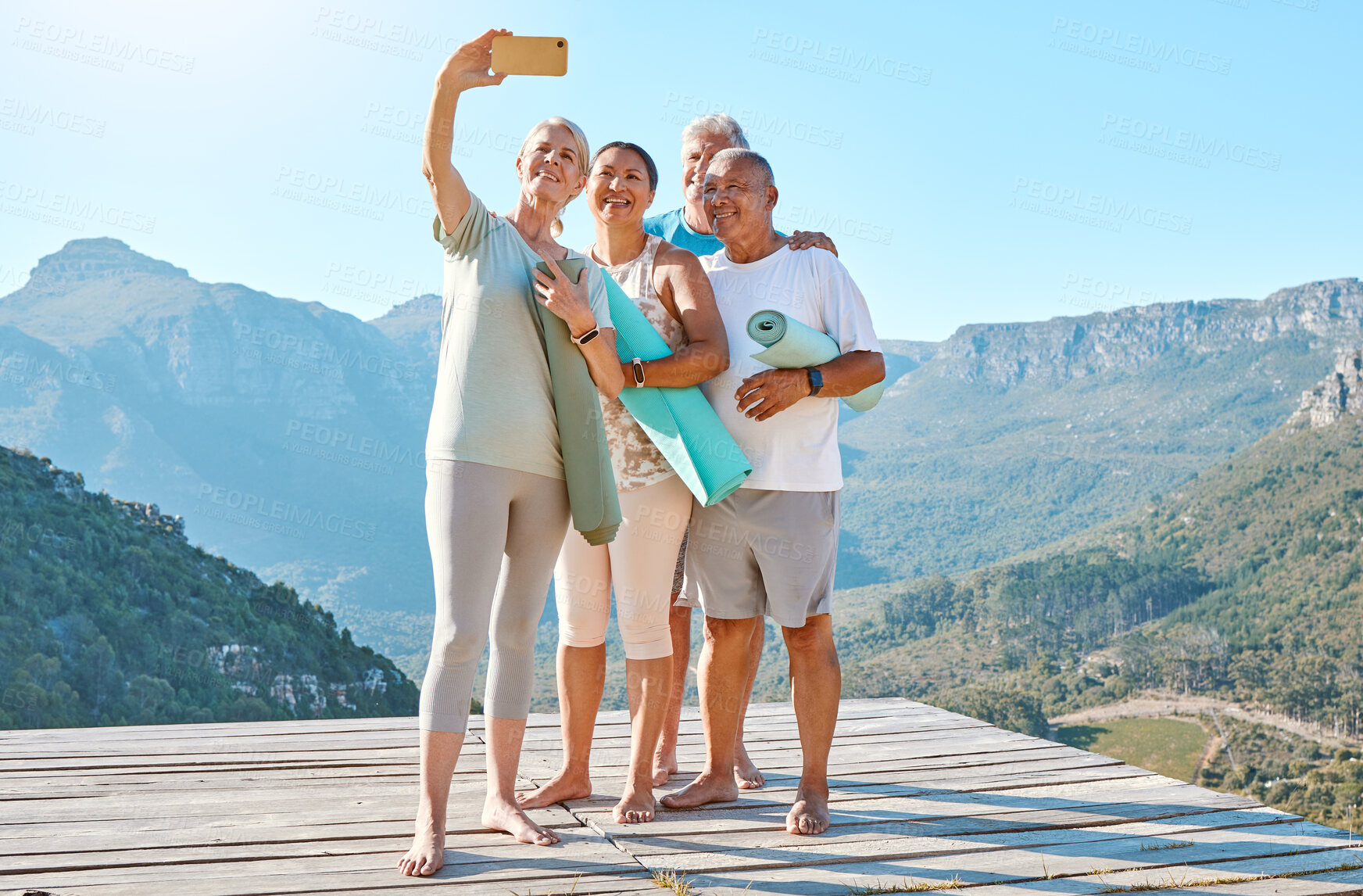 Buy stock photo Group of active seniors posing together for a selfie or video call on a sunny day against a mountain view background. Happy diverse retirees taking photo after group yoga session. Living healthy and active lifestyles