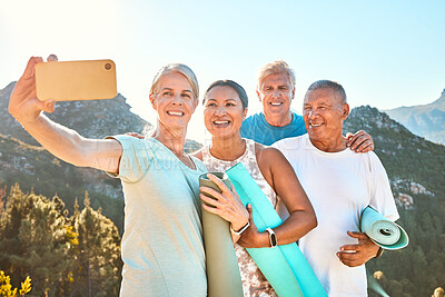 Group of active seniors posing together for a selfie or video call on a sunny day against a mountain view background. Happy diverse retirees taking photo after group yoga session. Living healthy and active lifestyles
