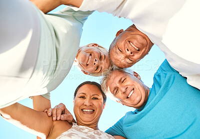 Buy stock photo Below portrait view of a group of senior friends standing together in a huddle. Smiling active senior people hugging while looking down at the camera